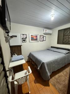 a bedroom with a bed and a desk and a television at Casa Recanto 2 quartos in Rio Verde