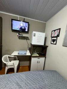 a bedroom with a bed and a desk with a tv on the wall at Casa Recanto 2 quartos in Rio Verde +7 photos