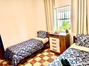 a bedroom with two beds and a dresser and a window at Guest House Rosa do Mar in Olinda