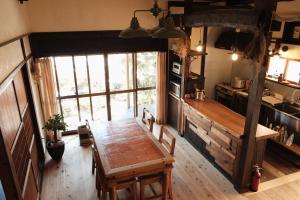 a kitchen with a wooden table and a large window at Guesthouse SHIGI in Nakatsugawa