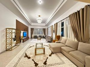 Una sala de estar con un sofá y un televisor en Oasis Villa Stay by Lunar, en Abu Dabi