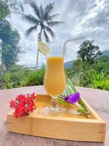 - un verre de jus d'orange sur un plateau en bois avec des fleurs dans l'établissement Bambua Nature Cottages, à Puerto Princesa