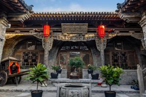 平遥Shanxi Merchant Mansion的一座有喷泉和植物的建筑
