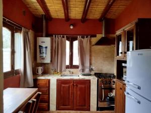 a kitchen with wooden cabinets and a white refrigerator at La Herencia Tilcara in Tilcara +11 photos