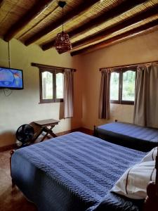 a bedroom with two beds and a tv and windows at La Herencia Tilcara in Tilcara