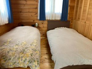 ein Schlafzimmer mit zwei Betten in einem Holzzimmer in der Unterkunft コテージコッタロ in Gojikkoku