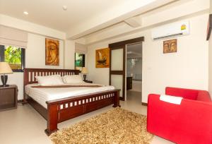 Un dormitorio con una cama y una silla roja. en Naiharn beach sands Apartment, en Nai Harn Beach 13 fotos más