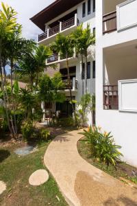 una pasarela frente a una casa con palmeras en Naiharn beach sands Apartment, en Nai Harn Beach