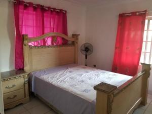 a bedroom with a bed with pink curtains at Diana place in Spanish Town +5 photos