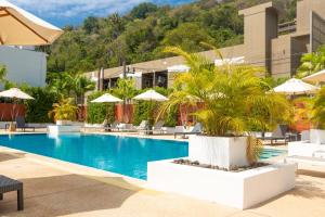 una piscina en un hotel con sillas y sombrillas en Naiharn beach sands Apartment, en Nai Harn Beach