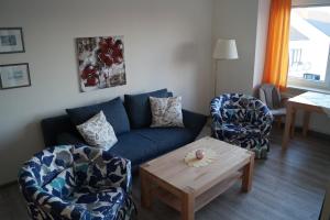 ein Wohnzimmer mit einem blauen Sofa und 2 Stühlen in der Unterkunft Appartementhaus Christel in Grömitz