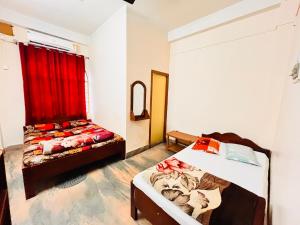 a bedroom with two beds and a red curtain at Lodge Bikash in Siliguri