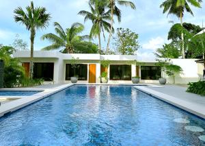 a swimming pool in front of a house with palm trees at La Vida Bonita Bed and Breakfast in San Vicente