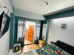 a bedroom with blue walls and a bed and a door at Blue Valley Apartment in Darjeeling