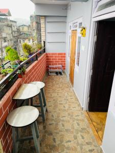 a balcony with two stools and a window at Blue Valley Apartment in Darjeeling