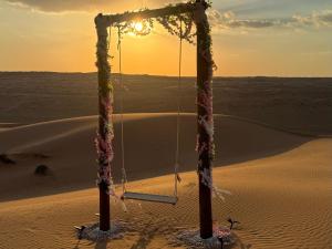 a swing in the desert with the sunset in the background at Infinity Camp in Bidiyah