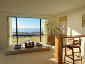 a living room with a desk and a table with a view at Panoramic Sea & Town View Oamaru 睁眼即见太平洋 I 躺观日月同辉 in Oamaru