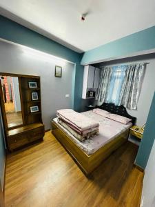 a bedroom with a bed and a blue wall at Blue Valley Apartment in Darjeeling