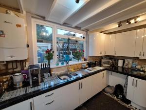 a kitchen with white cabinets and a sink and a window at The Old Chip Shop in Ilchester