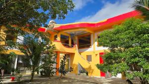 CabangusanEagle's Nest Inn的一座黄色和红色的建筑,前面有树木
