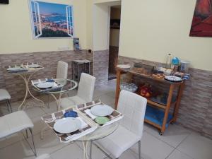 ein Esszimmer mit weißen Stühlen und einem Tisch mit Tellern in der Unterkunft B&B Quattro Palazzi Napoli Centro in Neapel