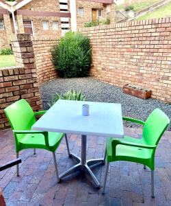 a white table and two green chairs on a patio at Studio 28 Clarens Apartment B in Clarens +2 photos