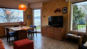 un salon avec une télévision et une table avec des chaises dans l'établissement Lago a colazione pranzo e cena, à Dormelletto