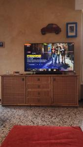 un téléviseur à écran plat posé sur un centre de divertissement en bois dans l'établissement Lago a colazione pranzo e cena, à Dormelletto