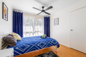 a bedroom with a bed with a blue comforter and a window at Picturesque Lakeside Getaway: Views, Beach, Park in Loch Sport