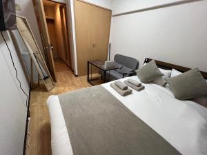 a bedroom with a large white bed and a chair at メゾンド天神 in Fukuoka