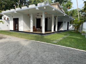 a white house with a porch and a driveway at Garden Villa in Kumbalgama