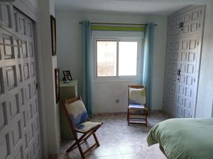 una camera da letto con due sedie e un letto e una finestra di COTOBRO - La Palmera Apt ad Almuñécar