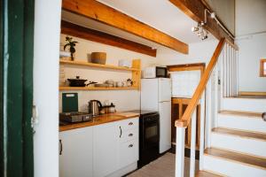 a kitchen with white cabinets and a white refrigerator at The Loft House in Graaff-Reinet