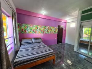 a bed in a room with a purple wall at Eagle's Nest Inn in Cabangusan