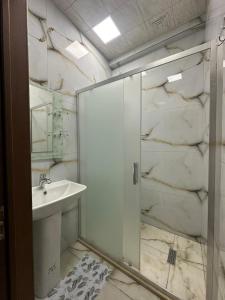 a bathroom with a glass shower and a sink at Narimanov Apartment in Baku