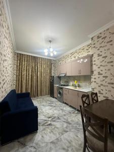 a living room with a blue couch and a kitchen at Narimanov Apartment in Baku