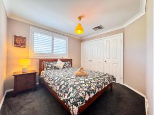 a teddy bear sitting on a bed in a bedroom at Blue Haven Retreat - Glenmore Park Pool Home in Glenmore Park