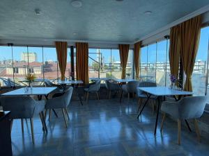 a restaurant with tables and chairs and large windows at Black Sea Star Batumi in Batumi