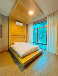 a bedroom with a bed and a large window at BIRD HOUSE resort in Hữu Biêt