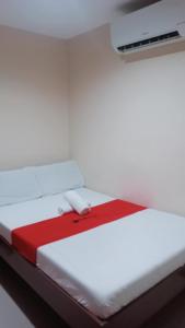 a white bed with a red blanket on it at WJV Inn Bohol in Tagbilaran City +1 photo