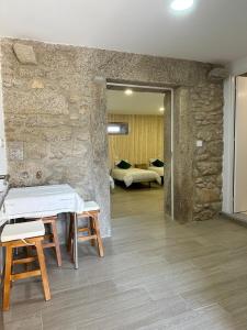 a room with a stone wall and a table and chairs at Forno House - Quarto peregrinos Caminho Santiago in Âncora