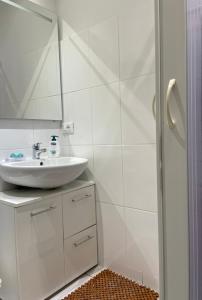 a white bathroom with a sink and a mirror at MiniLevico in Levico Terme +3 photos