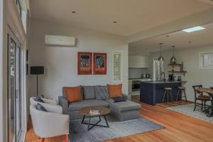 a living room with a couch and a table and a kitchen at Torbay Tree Tops in Auckland