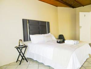 a bedroom with a large white bed with a black headboard at HavenNest in Rustenburg