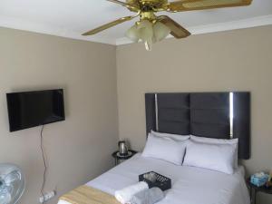 a bedroom with a bed with a ceiling fan at HavenNest in Rustenburg