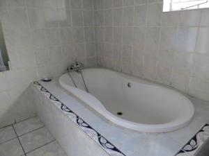 a white bath tub in a tiled bathroom at HavenNest in Rustenburg