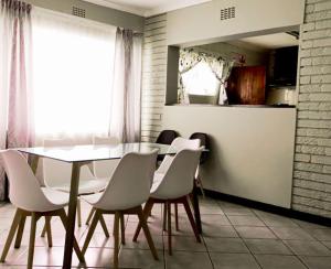a dining room with a table and white chairs at HavenNest in Rustenburg