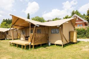 a row of tents in the grass in front of a house at Arden Parks Petite Suisse in Dochamps