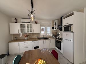a kitchen with white cabinets and a wooden table at AwayDays - Casa con Piscina in Empuriabrava