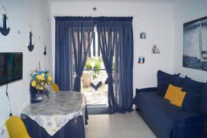 a living room with a blue couch and a table and a window at Fay's paradise in Polychrono